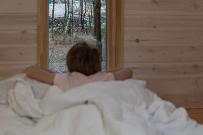 Rear view of woman relaxing on bed at home