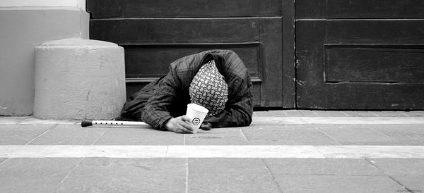 Beggar on sidewalk against building