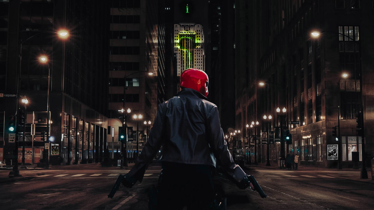 night, architecture, city, illuminated, street, built structure, building exterior, one person, real people, city life, street light, three quarter length, lifestyles, rear view, hood, clothing, building, standing, walking, hood - clothing