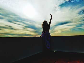 Rear view of silhouette woman standing against sky