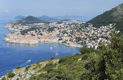 Aerial view of townscape by sea against sky