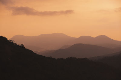 Scenic view of silhouette mountains against orange sky