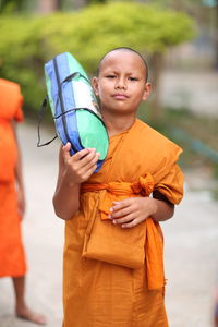 Happy boy holding camera while standing outdoors