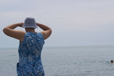 Rear view of woman standing at beach against clear sky