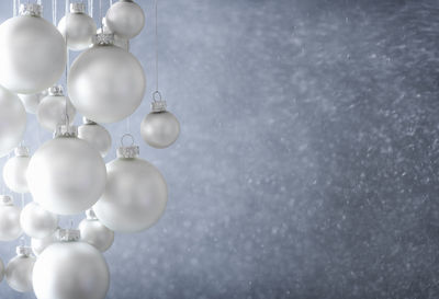 Close-up of white christmas ornaments hanging against gray wall