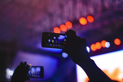 Close-up of hand holding smart phone at music concert