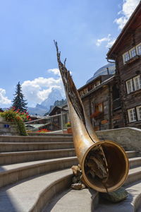 Bronze alphorn sculpture on stairs by day at zermatt, switzerland