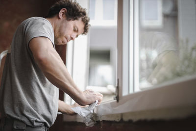 Caucasian man cleans the window frame.