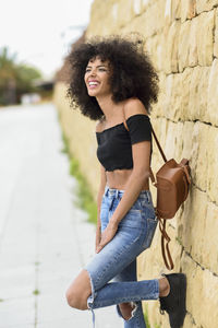 Mid adult woman with curly hair standing against wall