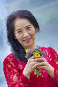 Portrait of a smiling young woman holding red flower