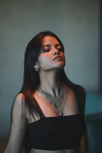 Portrait of young woman standing against wall