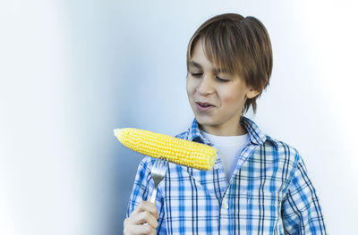 Smiling boy having corn against white background