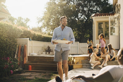 Happy man with food walking towards woman during garden party