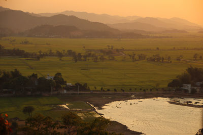 Scenic view of farm against sky during sunset