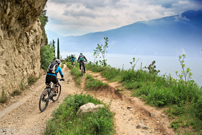 People riding bicycle on mountain against sky