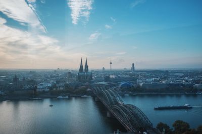 View of city at waterfront against cloudy sky
