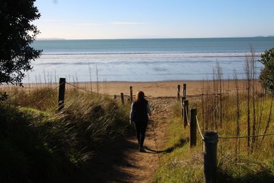 Woman walking on beach against clear sky