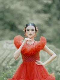Portrait of young woman standing against trees