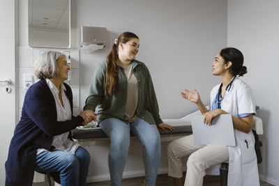 Female doctor explaining patient sitting with mother in clinic