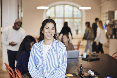 Portrait of smiling female entrepreneur wearing striped shirt at coworking office