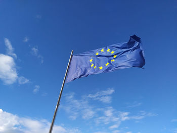 Low angle view of flag against blue sky