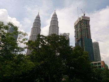 Low angle view of skyscrapers against cloudy sky