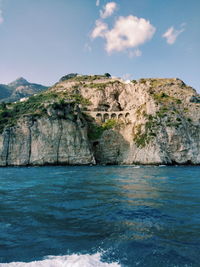 Scenic view of sea by cliff against sky