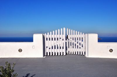 Built structure by sea against clear blue sky