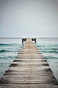 Jetty leading to calm sea against clear sky