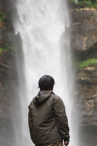 Rear view of man looking at waterfall