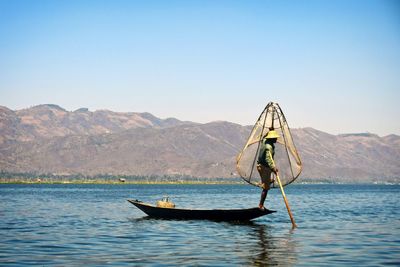 Man in boat on lake against mountain range