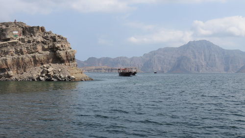 Boats moving in sea against cloudy sky