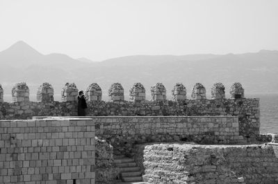 Woman standing at historic building against sky