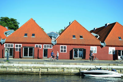 Houses by river and buildings against sky