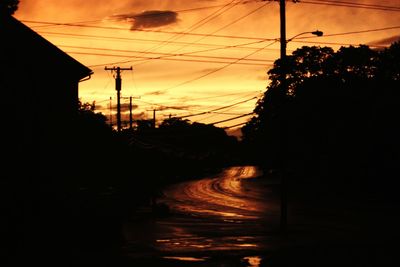 Silhouette electricity pylon against sky during sunset