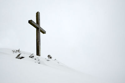 Cross on snow against clear sky