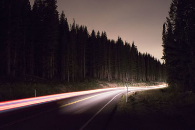 Light trails on road against sky at night