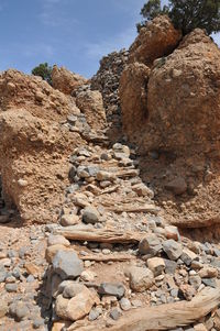 Stone wall by rock formation against sky
