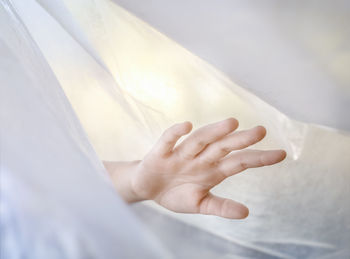 Close-up of human hand amidst white textile