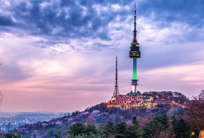 Communications tower in city against sky