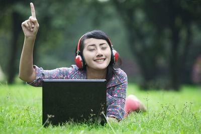 Smiling woman listening music at lawn
