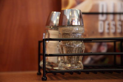 Close-up of salt and pepper shakers in metal container on table