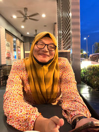 Portrait of smiling woman wearing hijab sitting at restaurant