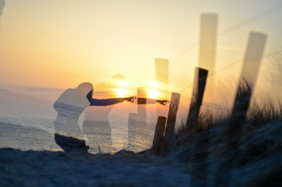 Digital composite image of woman at beach against sky during sunset