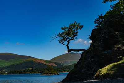 Scenic view of sea and mountains against clear blue sky