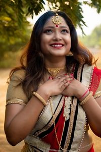 Smiling young woman in sari looking away against trees