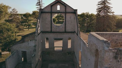 Old building by trees against sky