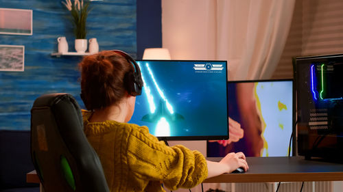 Rear view of woman using phone while sitting on table