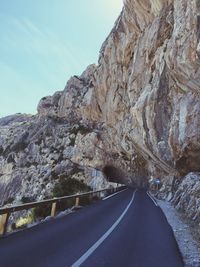 Empty mountain road leading towards cave