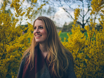 Young woman standing against trees